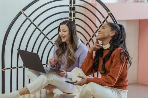 Two happy women making purchase in front of a laptop because of SEO benefit